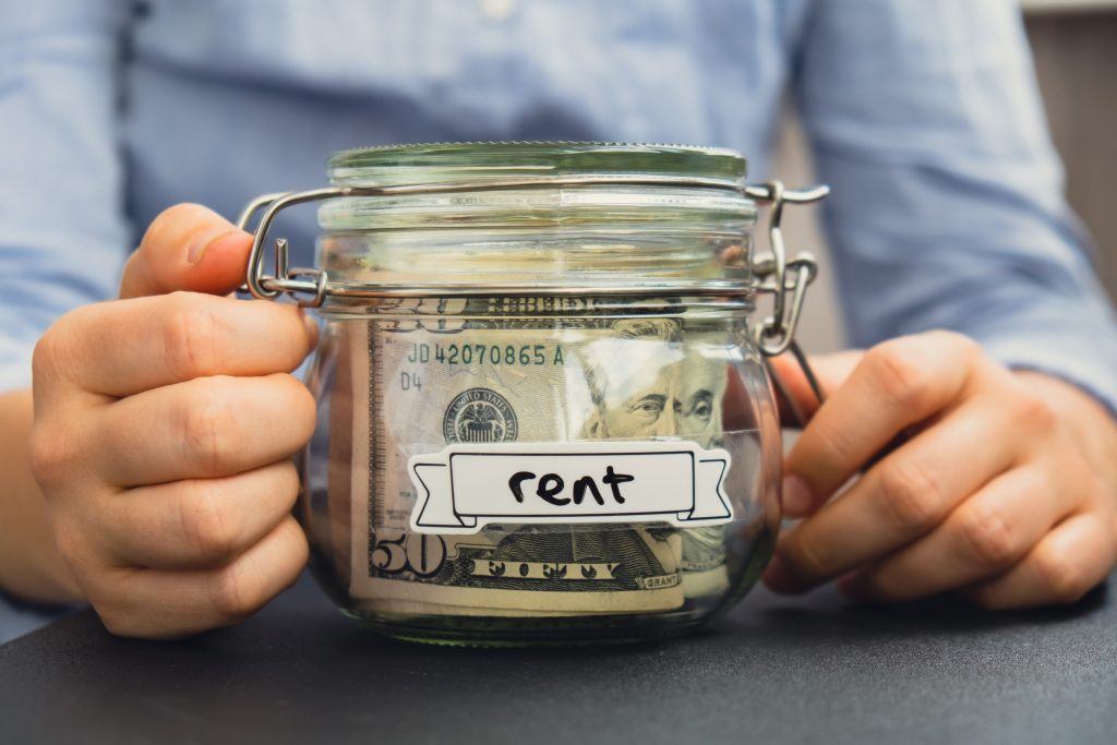 a renter holding a jar of cash labeled rent