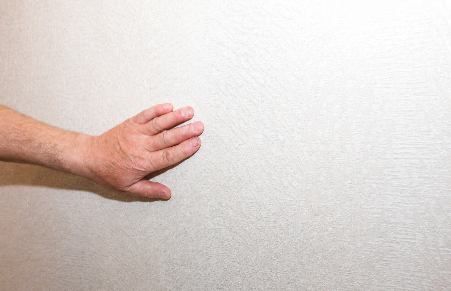Hand gently exploring the textured surface of a wall, showcasing the intricate details and tactile experience.