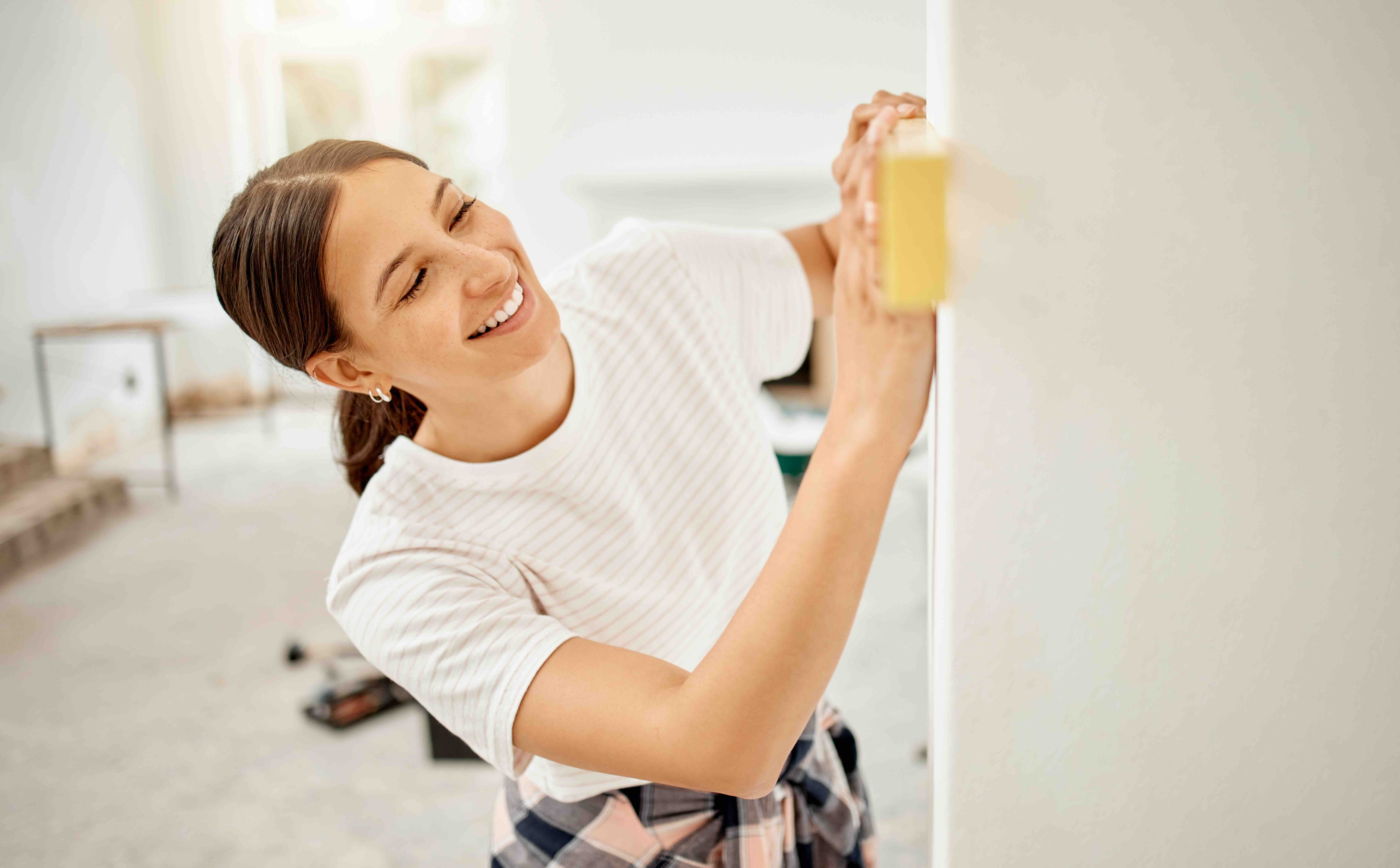 Renter using a level to ensure a straight installation on an apartment wall, demonstrating home improvement skills.